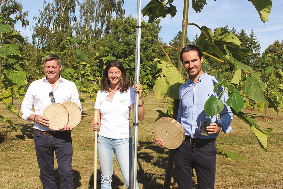 Benjamin Carrion et Baptiste Mauviel, co-fondateurs de la société Paulownia Nature, entourent Lucile Mauviel. Ils présentent le bois obtenu et un plant.