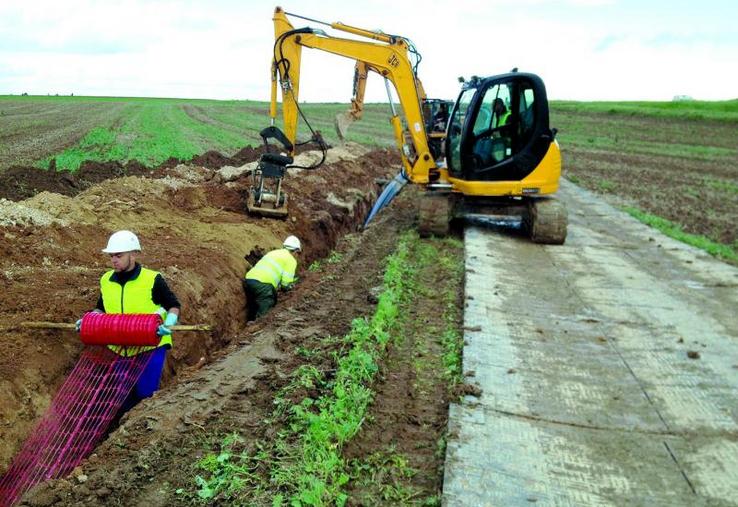 La pose à la trancheuse est théoriquement plus rapide, mais la tranchée traditionnelle avec piste protégée est moins sensible aux conditions humides.