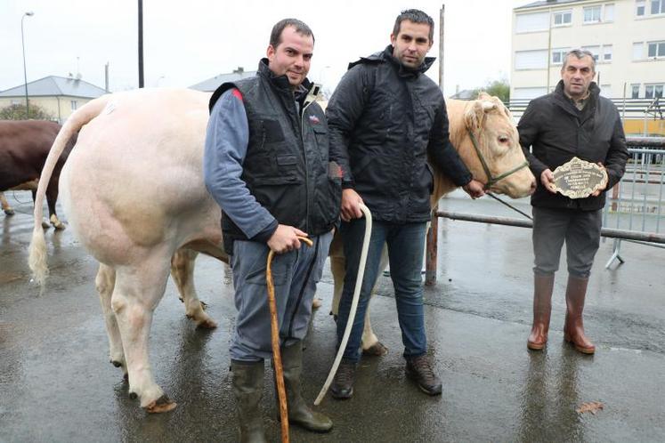 Didier Carré (à droite), accompagné de son fils et d’un ami, pose fièrement avec sa plaque et la Charolaise primée à l’inter-races femelle, samedi 1er décembre 2018 à Évron.