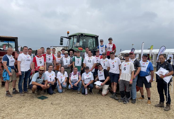 Les 11 candidats au concours de labour, devant les charrues, prêts à concourir, aux côtés des membres du jury.