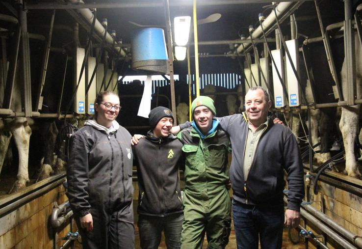 Amélie, Nathan, Clément, et Denis Piednoir dans la salle de traite.