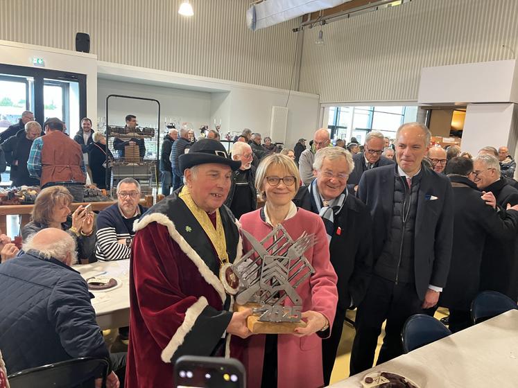 Véronique Louwagie tient le trophée du concours du meilleur boudin noire organisé par la confrérie du goûte boudin de Mortagne, représentée ici par son président.