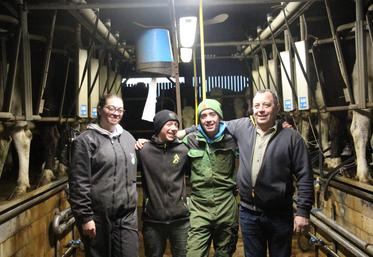 Amélie, Nathan, Clément, et Denis Piednoir dans la salle de traite.