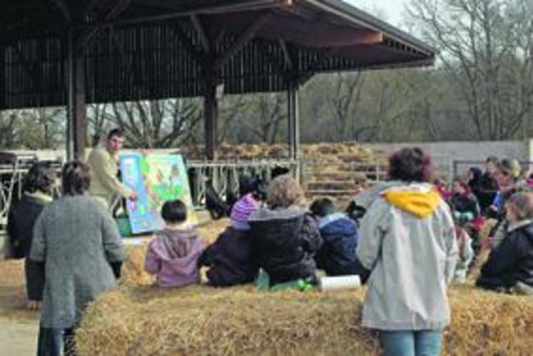 Les enfants, installés sur la paille, écoutent attentivement les explications de Bertrand Rochais.