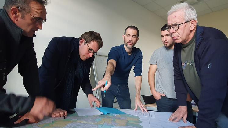 Un groupe d'hommes rassemblés autour d'une carte posée sur une table.