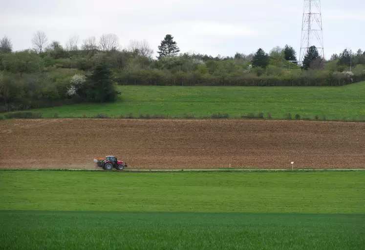 Paysage agricole de grande culture en Bougogne-Franche-Comté (Côte-d'Or) au printemps avec tracteur qui traverse au centre de l'image.