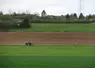 Paysage agricole de grande culture en Bougogne-Franche-Comté (Côte-d'Or) au printemps avec tracteur qui traverse au centre de l'image.