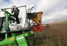 Salarié agricole apportant de l'engrais organique sur une parcelle de vigne en bio.