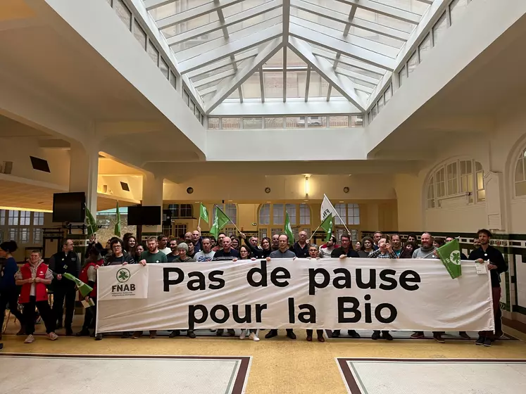 Des agriculteurs bio devant une banderole avec le message "pas de pause pour la bio"