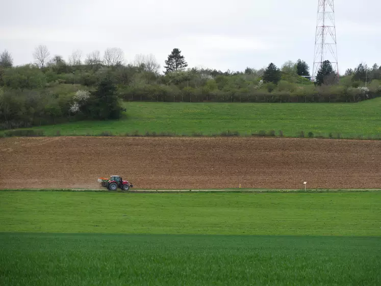 Paysage agricole de grande culture en Bougogne-Franche-Comté (Côte-d'Or) au printemps avec tracteur qui traverse au centre de l'image.