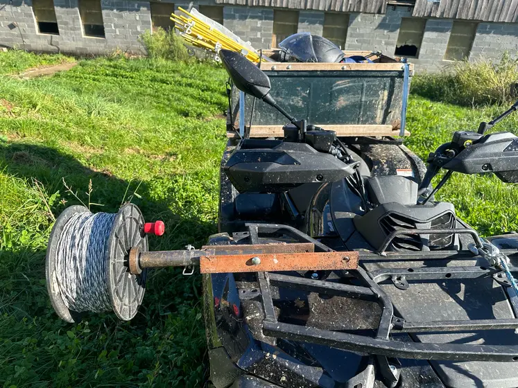 Sur le quad, l'éleveur fixe la bobine de fil de clôture. Les piquets sont rangés à l'arrière.