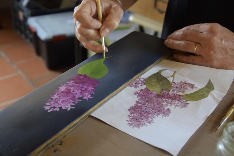 Leslie Gaillard peint sur des douelles de barriques.