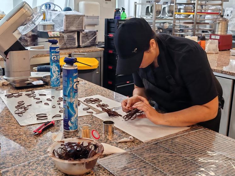 Une apprentie en chocolaterie en pleine réalisation de détails.