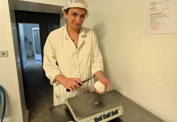 Fromagère qui coupe un fromage au-dessus d'une balance