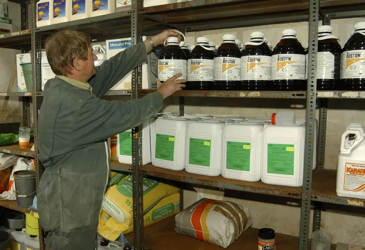 Un agriculteur de profil fouille dans son local de produits phytosanitaires.