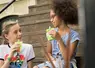 deux enfants qui consomment des compotes de fruits en gourde