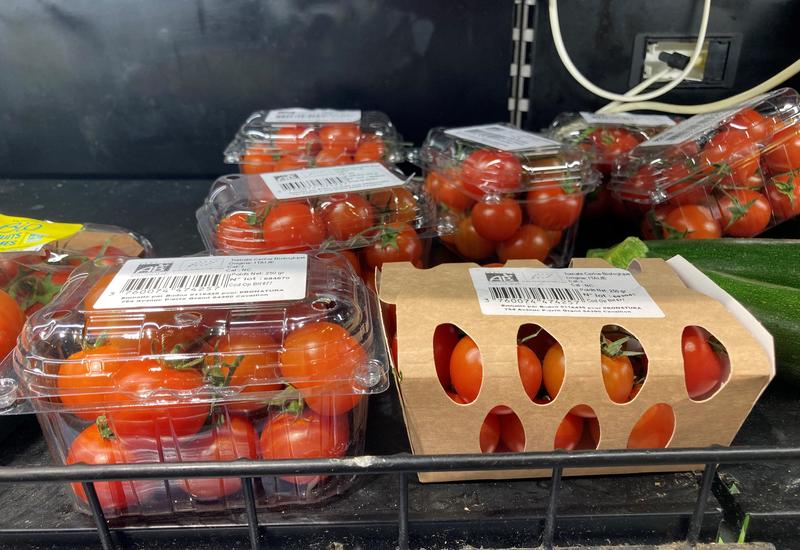 Barquettes de tomates cerise avec au premier plan une barquette en plastique et une en carton. 