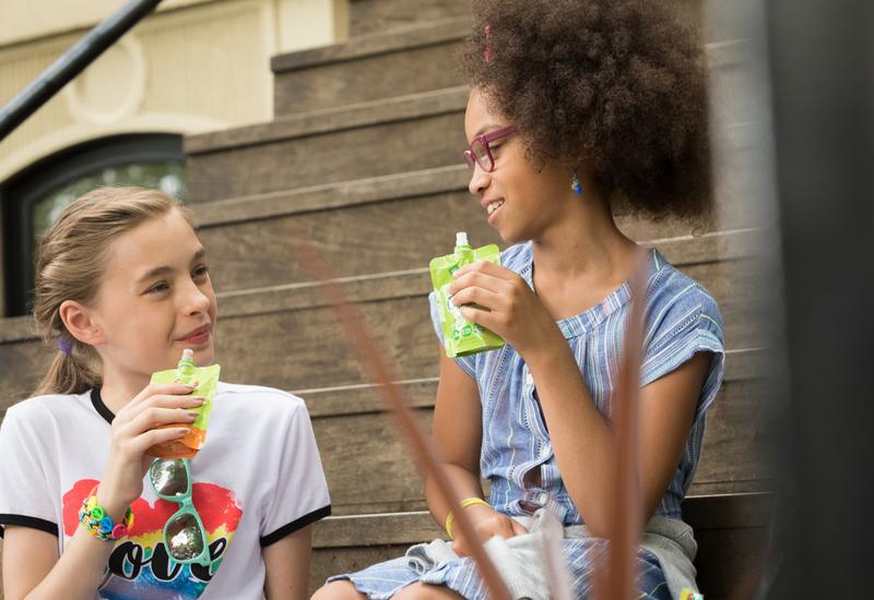 deux enfants qui consomment des compotes de fruits en gourde