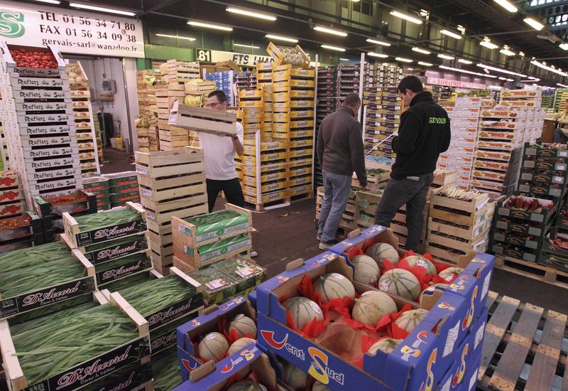 Rayon fruits et légumes au Marché d' intérêt national de Rungis. Etalage d' un grossiste au MIN. Distribution de produits frais français et internationaux. Cartons de melons et cageots d' haricots gourmands.