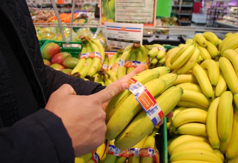 Une main de bananes enrubannée en bleu blanc rouge, dans un rayon de fruits et légumes de la grande distribution.