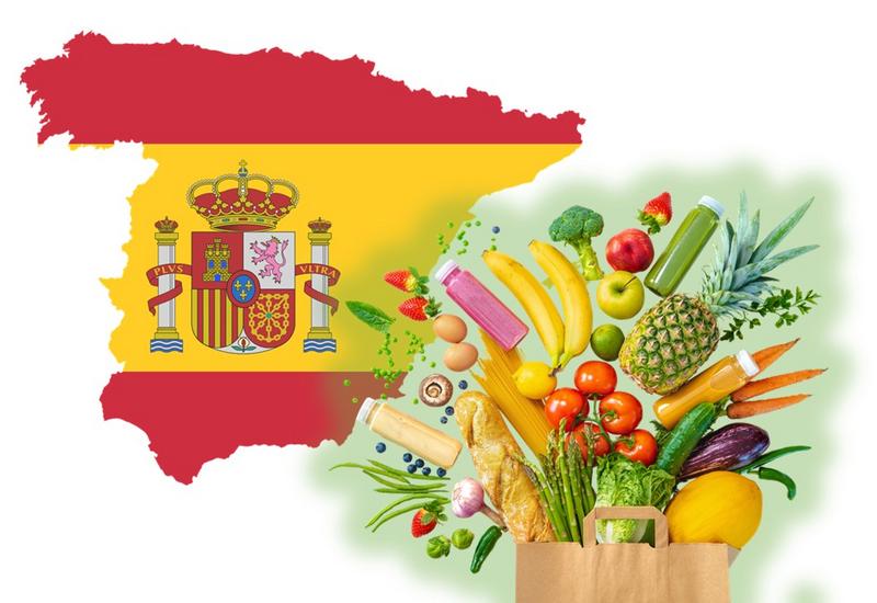 drapeau espagnol à la forme du pays; et un sac kraft débordant de fruits et légumes