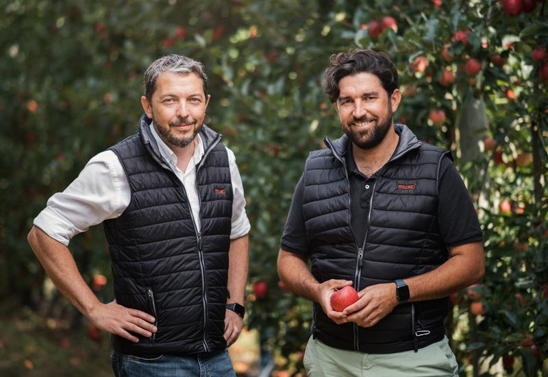 Deux producteurs de pommes posent dans leur verger