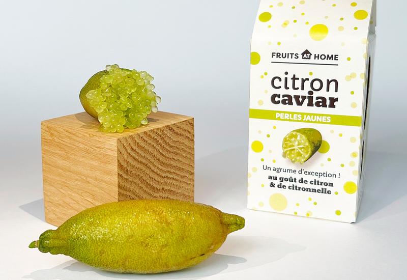 Un citron caviar jaune entier, un autre coupé et leur emballage de la gamme de Fruits at Home.