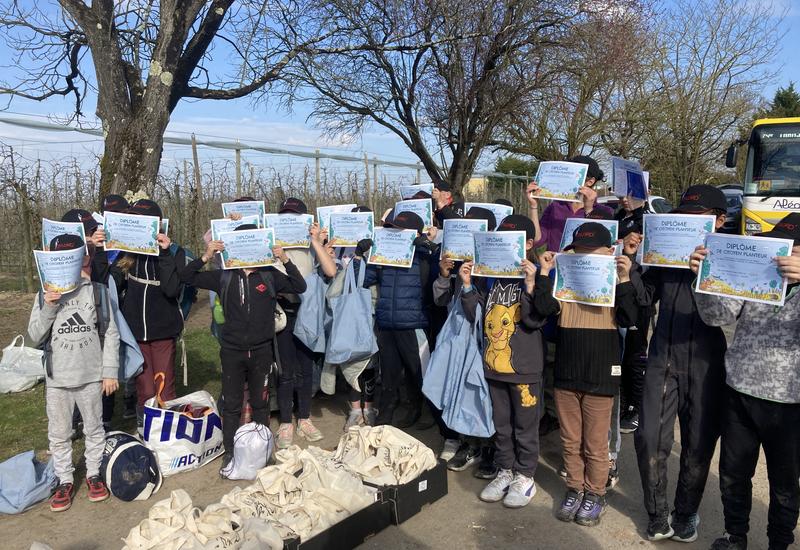 des enfants tiennent devant leur visage un diplôme de "citoyen planteur"