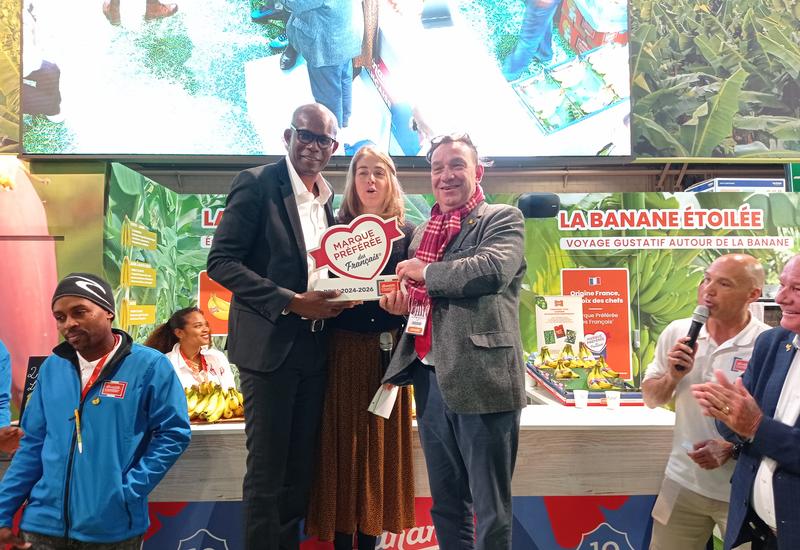 Trois personnes tiennent un prix sur un podium, sur un stand au salon de l'agriculture