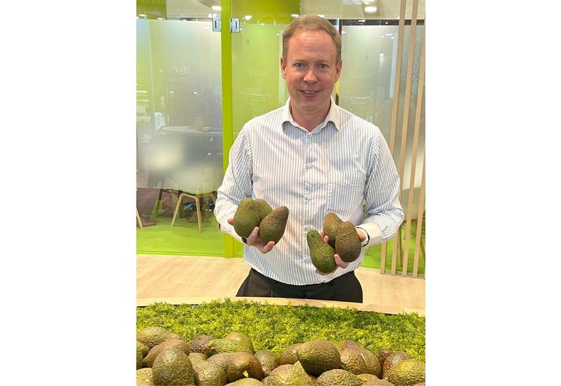 Zac Bard président de la WAO sur un stand à Fruit Logistica tient dans ses mains des avocats
