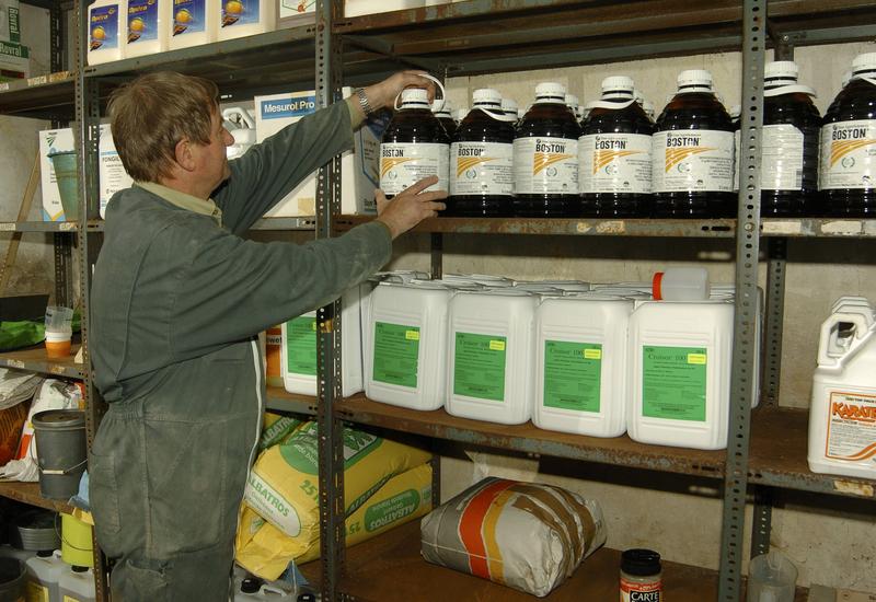 Un agriculteur de profil fouille dans son local de produits phytosanitaires.