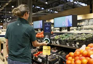 Dans un rayon fruits et légumes, une personne scanne un avocat