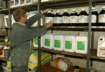 Un agriculteur de profil fouille dans son local de produits phytosanitaires.