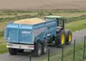 Tracteur sur la route avec une remorque remplie de grain de blé à livrer
