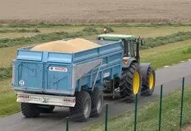Tracteur sur la route avec une remorque remplie de grain de blé à livrer