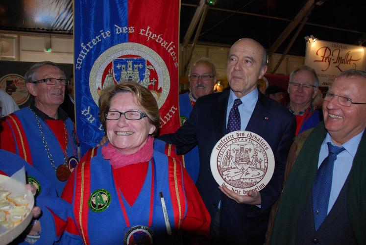 Les confréries des bries de Melun et de Meaux sont toujours présentes sur la foire. Ici aux côtés du nouveau président du comité de foire, André Mouilleron, Alain Juppé s’est vu remettre des morceaux de brie — ici le M’lun.

