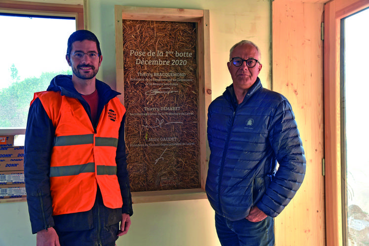 Aymeric Prigent et Thierry Bracquemond, devant la fenêtre de vérité du bâtiment permettant de voir l'isolation en paille.