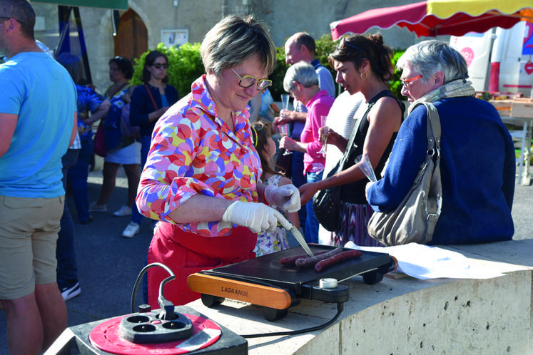 Sous un grand soleil de mai, Mireille Moron prépare ses saucisses à la plancha pour l'apéritif organisé à la fin du marché du Loury.