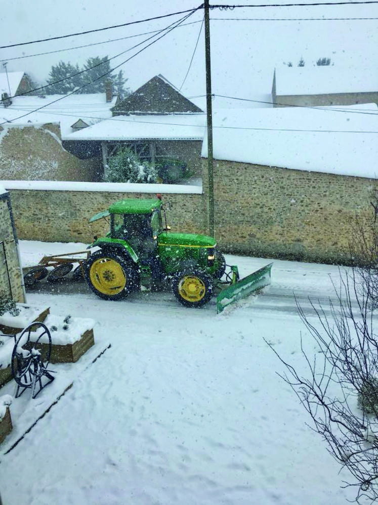 Un tracteur muni d'une lame de déneigement en action.