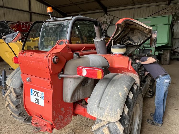 Un agriculteur entretient son chargeur télescopique.