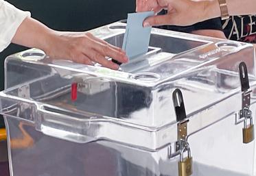 Un citoyen s'apprête à laisser son bulletin de vote dans l'urne.