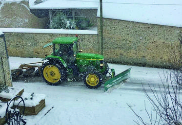 Un tracteur muni d'une lame de déneigement en action.