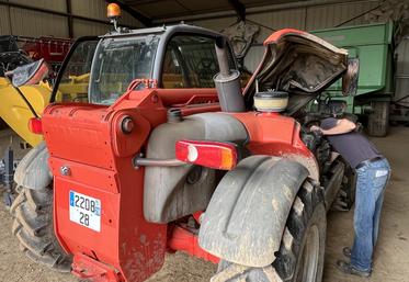 Un agriculteur entretient son chargeur télescopique.