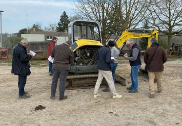 Les participants à la formation apprennent à vérifier une mini-pelle. 