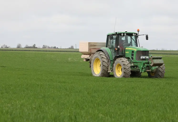 Tracteur qui épand des engrais dans un champ de blé.