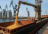 Image d'un chargement de blé sur un cargo dans un port maritime.