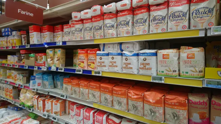 Rayon de supermarché avec des paquets de farine de toutes marques.