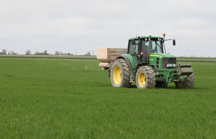 Tracteur qui épand des engrais dans un champ de blé.