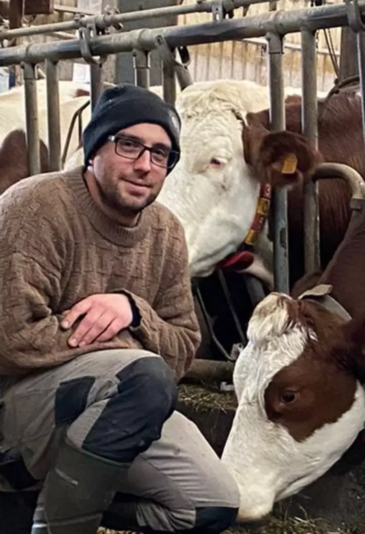 Samuel Bouchier, en EARL dans l'Isère, posant devant ses vaches au cornadis