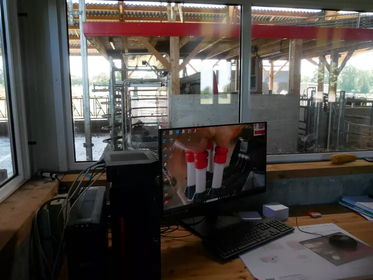 Bureau de l'éleveur avec vue sur le robot de traite et le stabulation des vaches laitières.